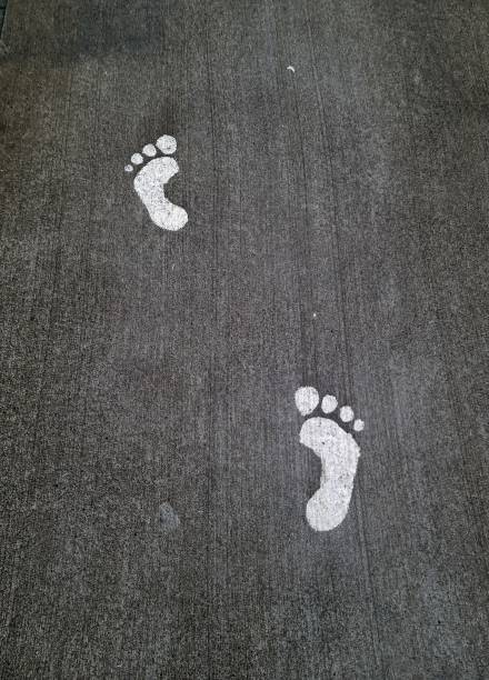 istock White footprints showing walking direction on asphalt road 2205372612