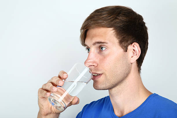 istock Beautiful young man drinking water on grey background 2205375432