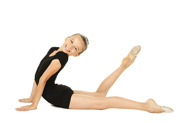 Cute elementary age girl gymnast dressed in gymnastics uniform performing a flexibility and stretching. She doing the basic shapes in gymnastics. Studio shot on white background