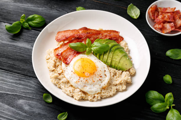 istock Savory Oatmeal breakfast with sunny side up fried egg, bacon and avocado. Healthy food 2205382034