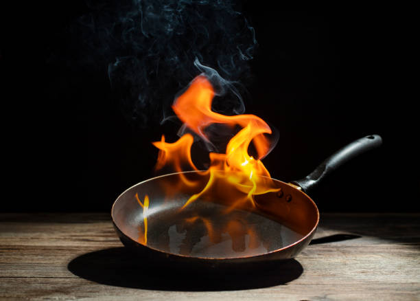 istock Black cooking pan with flames placed in kitchen on dark background table. 2205385908