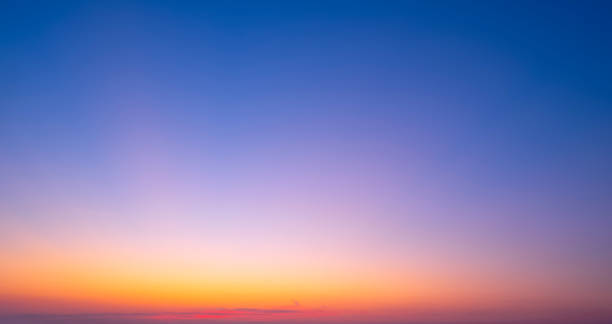 Evening sky background with natural gradient light on colorful orange and blue dusk sky after sundown