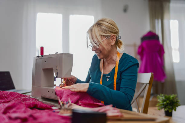 istock Senior woman using a sewing machine in a cozy home setting, surrounded by fabrics and threads, showcasing creativity and craftsmanship in textile work 2205386516