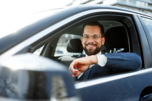 Joyful driver smiles while holding the wheel, cruising down the road in a well-equipped vehicle