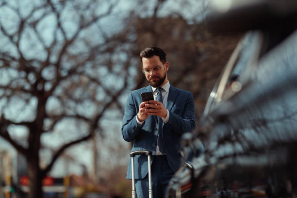 istock Businessman With Suitcase Checking Phone 2205387570