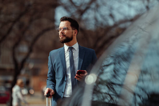 istock Businessman With Suitcase Checking Phone 2205387571