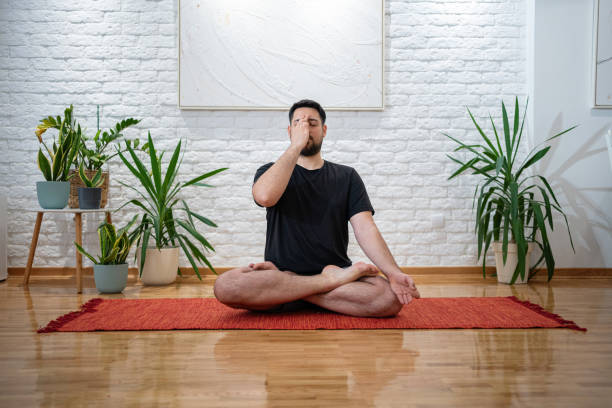 istock Man Practicing Yoga Breathing Exercises in a Modern Home Interior 2205391304