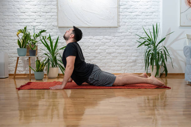 istock Man Practicing Yoga Exercise at Home with Plants and Wooden Flooring 2205391313