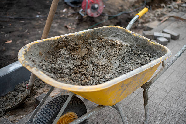 istock Urban Roadwork. Yellow Wheelbarrow with Cement and Sidewalk Paving 2205391441