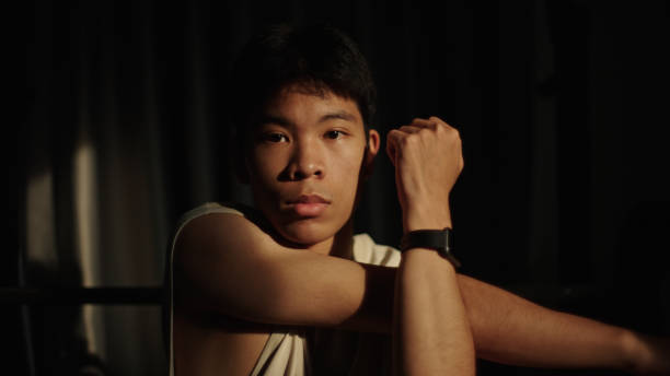 Asian teenager stretching pre weight training at gym.