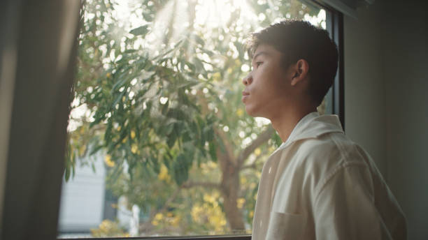 istock Teenager looking through the window. 2205392697