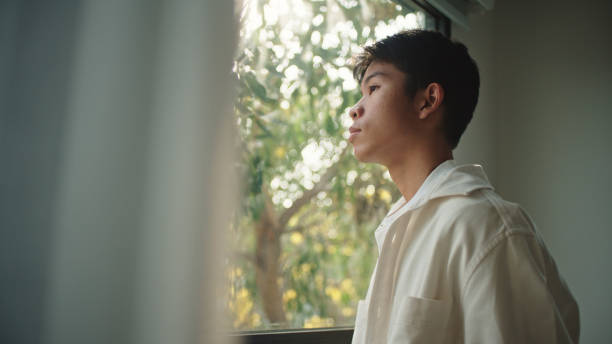 istock Teenager looking through the window. 2205392698