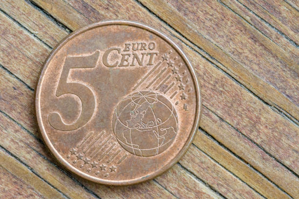 A macro image of a 5-cent euro coin placed on a wooden background, symbolizing microtransactions and economic value.