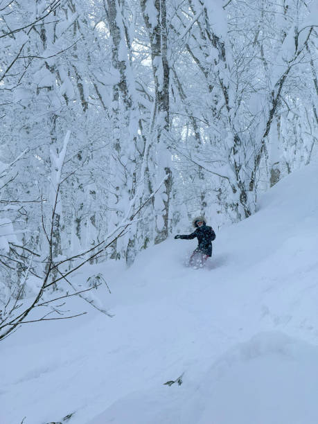 istock VERTICAL: A young female snowboarder makes her way down a secluded forest trail. 2205394363