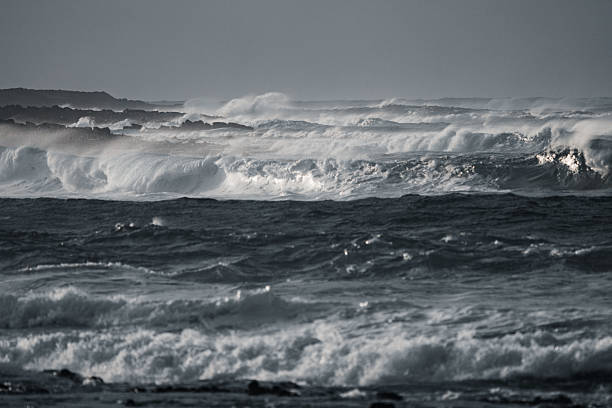 Massive ocean waves crash with power and intensity under a dark sky. The dynamic motion and deep blue tones capture the raw force of nature in this dramatic seascape.