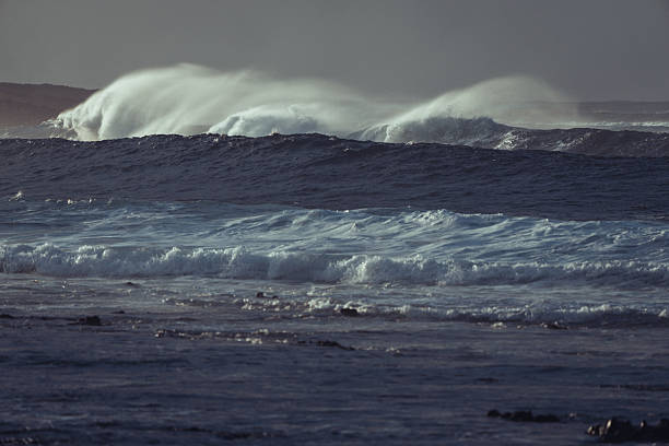 Small wave in the ocean with cloudy sky.