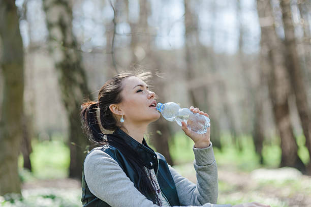 istock A girl is drinking water from a plastic bottle in a spring forest 2205398764