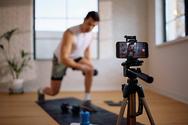 istock Close up of fitness instructor recording exercise tutorial with smart phone. 2205402207