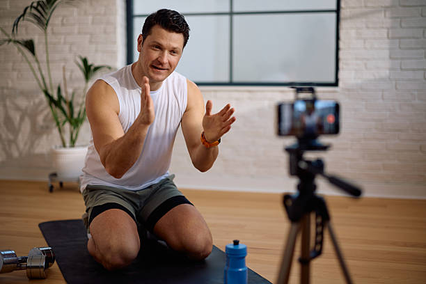 istock Smiling coach talking while recording exercise vlog at his fitness studio. 2205402554