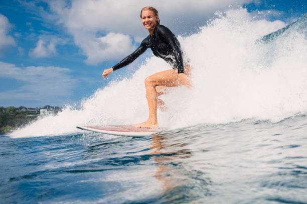 istock Female surfer riding a perfect breaking wave on a sunny day 2205402563