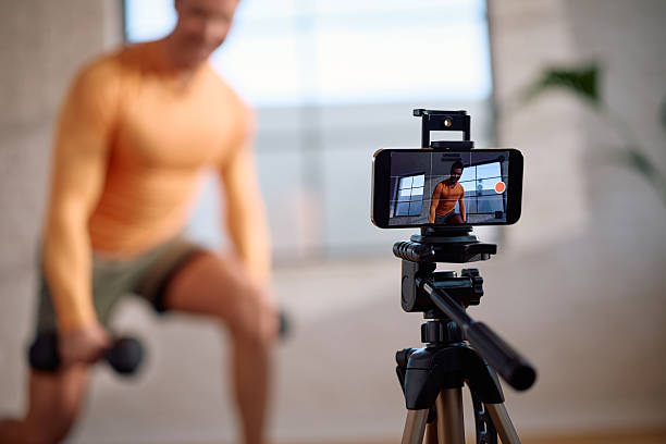 istock Close up of fitness instructor recording workout tutorial with smart phone. 2205402612