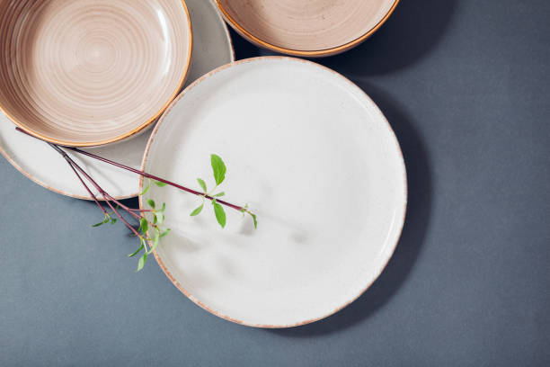 istock Close up of glazed ceramic kitchenware on grey background. Set of white beige dinner and soup plates 2205404190