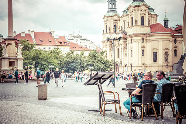 Prague, Czech Republic - June, 12, 2024:  People enjoy sitting a busy tourist morning in the Old Town Square, Prague.