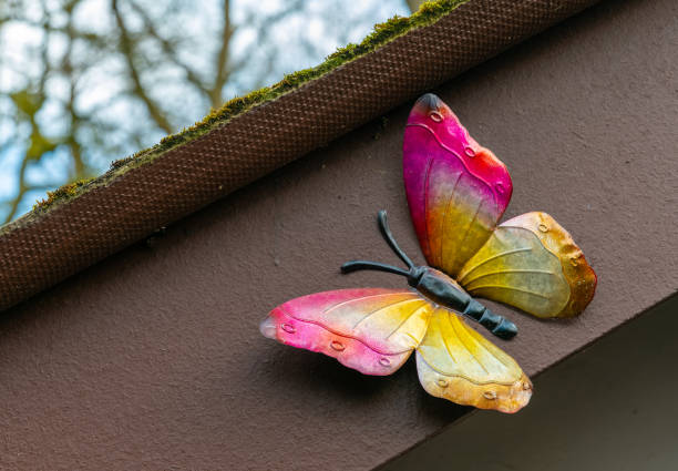 Colorful butterfly decoration on a garden shed in springtime bloom near tall trees under a bright blue sky stock photo