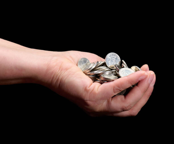 istock Hand holding a pile of silver coins on a black background 2205421343