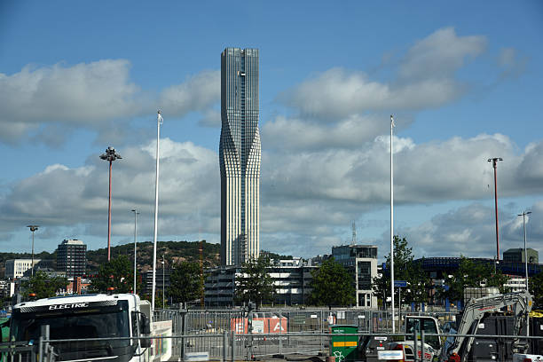 This image shows Kaknästornet, a prominent communication tower located in Stockholm, Sweden. The tower stands tall and is constructed from concrete, featuring multiple levels equipped with antennas and broadcasting equipment. It rises above a dense forest, highlighting its significant height and importance in the region's telecommunication infrastructure.