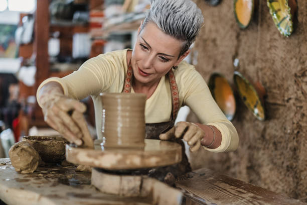 Young women, making clay pottery on a pottery wheel in the art studio horizontal shot