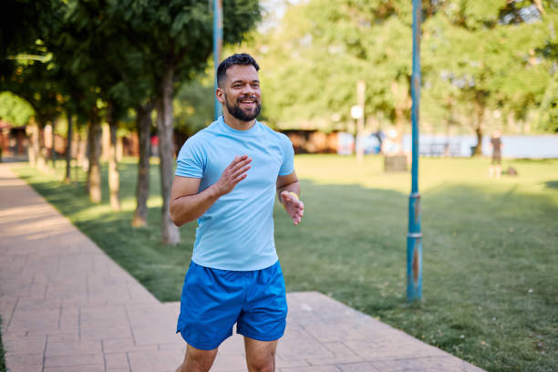 istock Young man jogging in the park enjoying his workout 2205433559