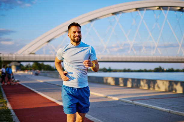 istock Young man jogging near the river under a bridge 2205434203