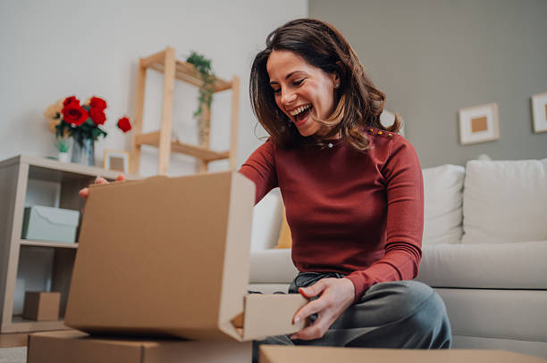 Happy woman opening a package at home, discovering a gift