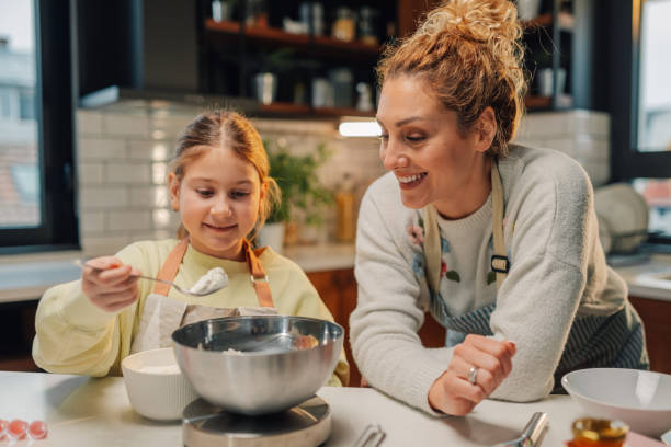 istock Mother and daughter baking together, adding ingredients to mixing bowl in kitchen 2205435941