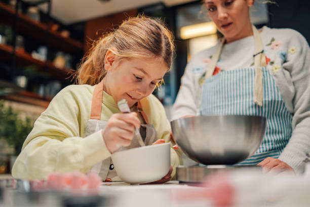 istock Young girl adding ingredients while baking with her mother in the kitchen 2205435947