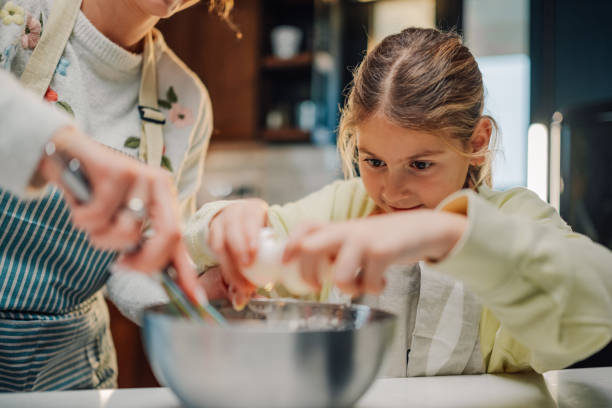 istock Little girl adding ingredients while baking with her mother in the kitchen 2205435957