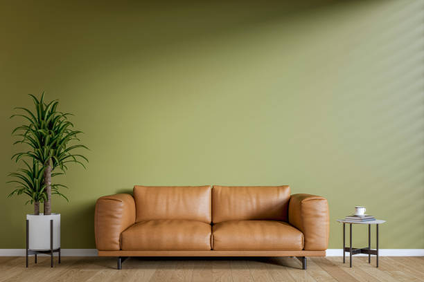 istock Modern interior: a living room with a brown sofa, low side table, khaki (olive green) plaster wall background and decoration 2205436415