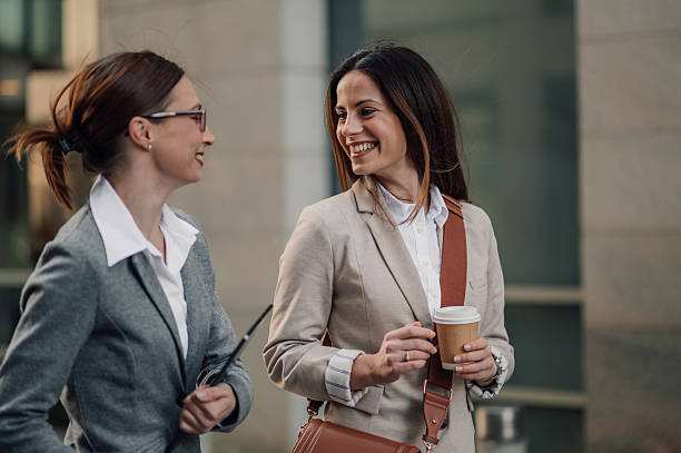 istock Two businesswomen walking and talking outdoors during coffee break 2205436501
