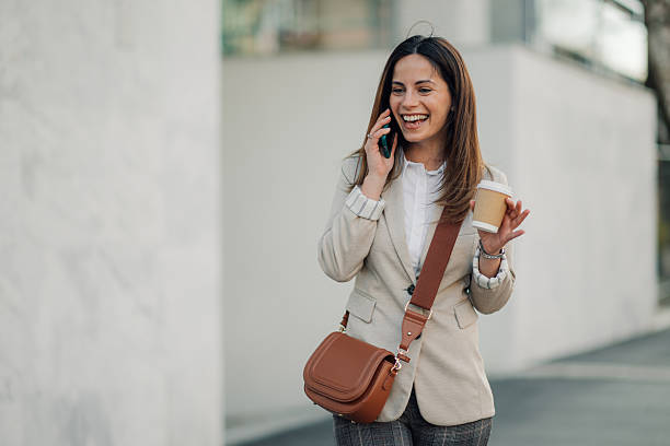 istock Businesswoman walking and talking on phone while holding coffee 2205436534