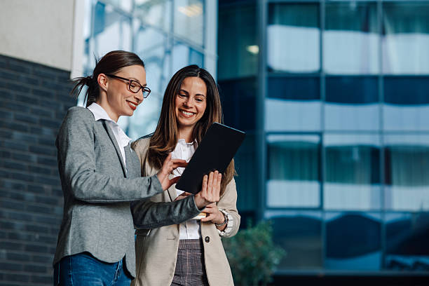 istock Two businesswomen collaborating on a digital tablet outside office building 2205436543