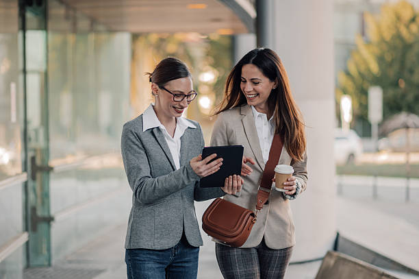 istock Two businesswomen walking and using a digital tablet outside office building 2205436546