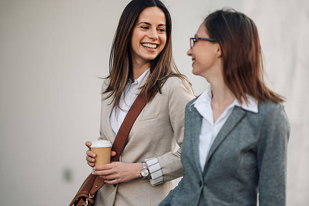 istock Two businesswomen walking and talking during coffee break 2205436551