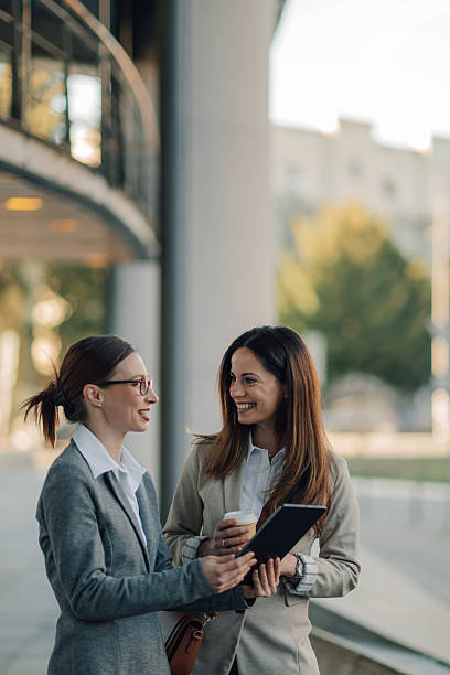 istock Businesswomen having a conversation and using digital tablet outdoors 2205436583