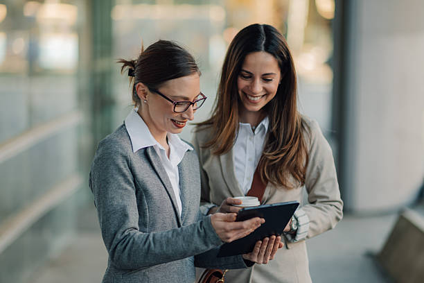 istock Two businesswomen using digital tablet outside office building 2205436604