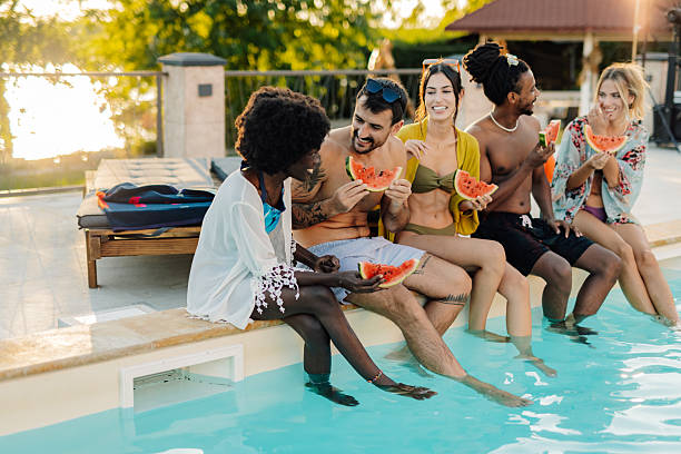 istock Friends eating watermelon by the poolside during summer vacation 2205437459
