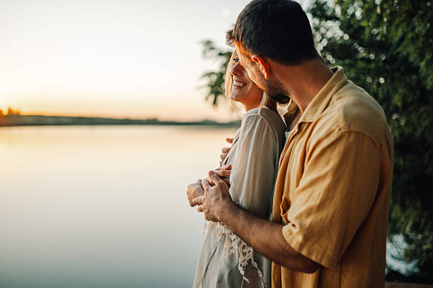 istock Romantic couple embracing by the lake at sunset 2205437696