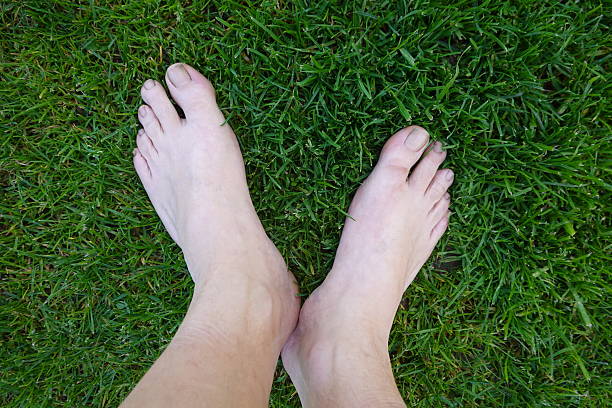 istock Barefoot person standing on green grass enjoying summer 2205439959
