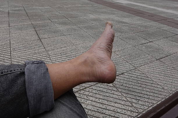 Man relaxing barefoot on pavement, showcasing his feet and jeans while enjoying a leisurely moment in an urban outdoor setting