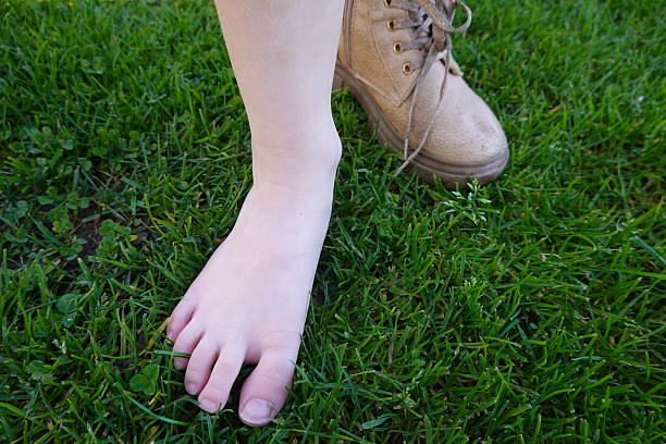 Child feeling the pleasure of walking barefoot on a green lawn, enjoying nature and freedom